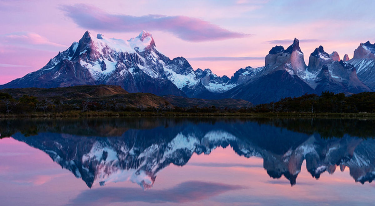 torres del paine mountain's image is reflected on the water while the sky on the background is a mix of purples, pinks, and blues