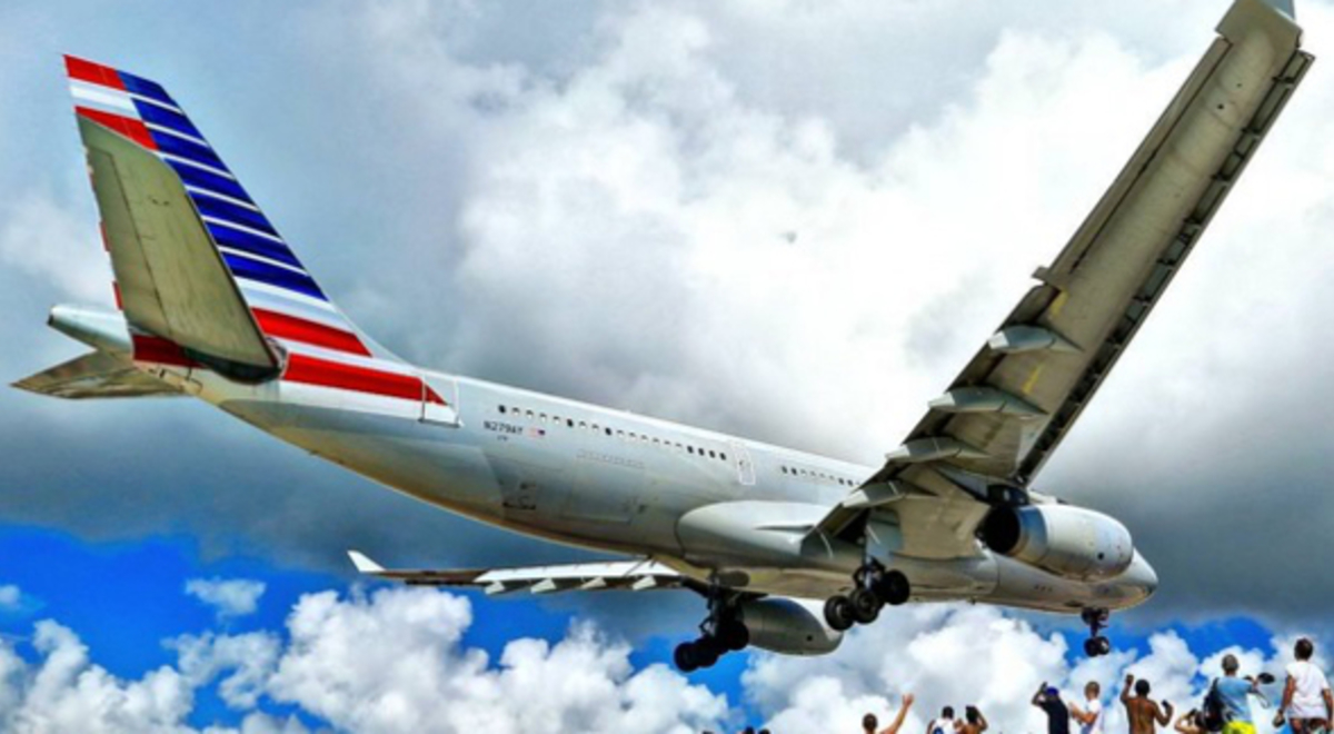 Group of people on the ground waving to a landing plane 