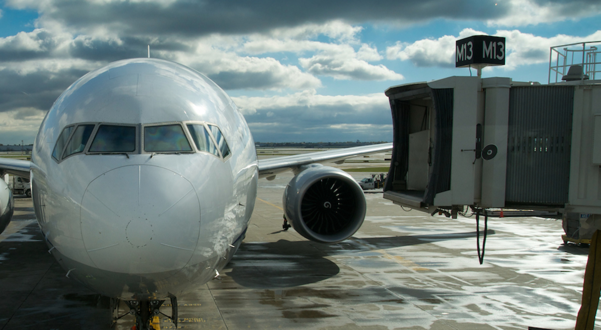 Front- on view of a plane on an airport tarmac with a second plane coming past behind it
