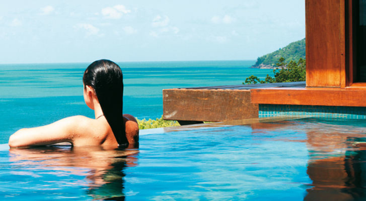Woman in pool looking towards the ocean 