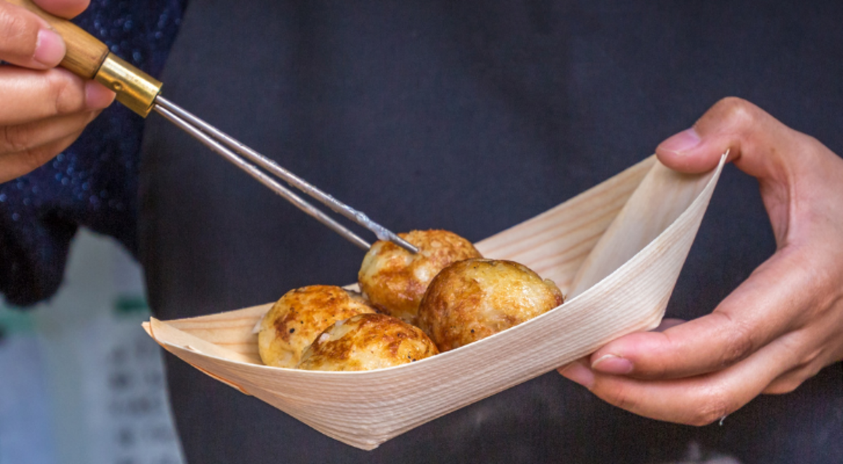 Man eating street foods using metal chopsticks