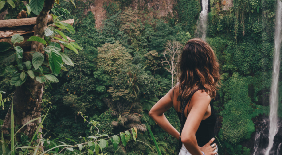 Lady admiring the waterfalls in the forest
