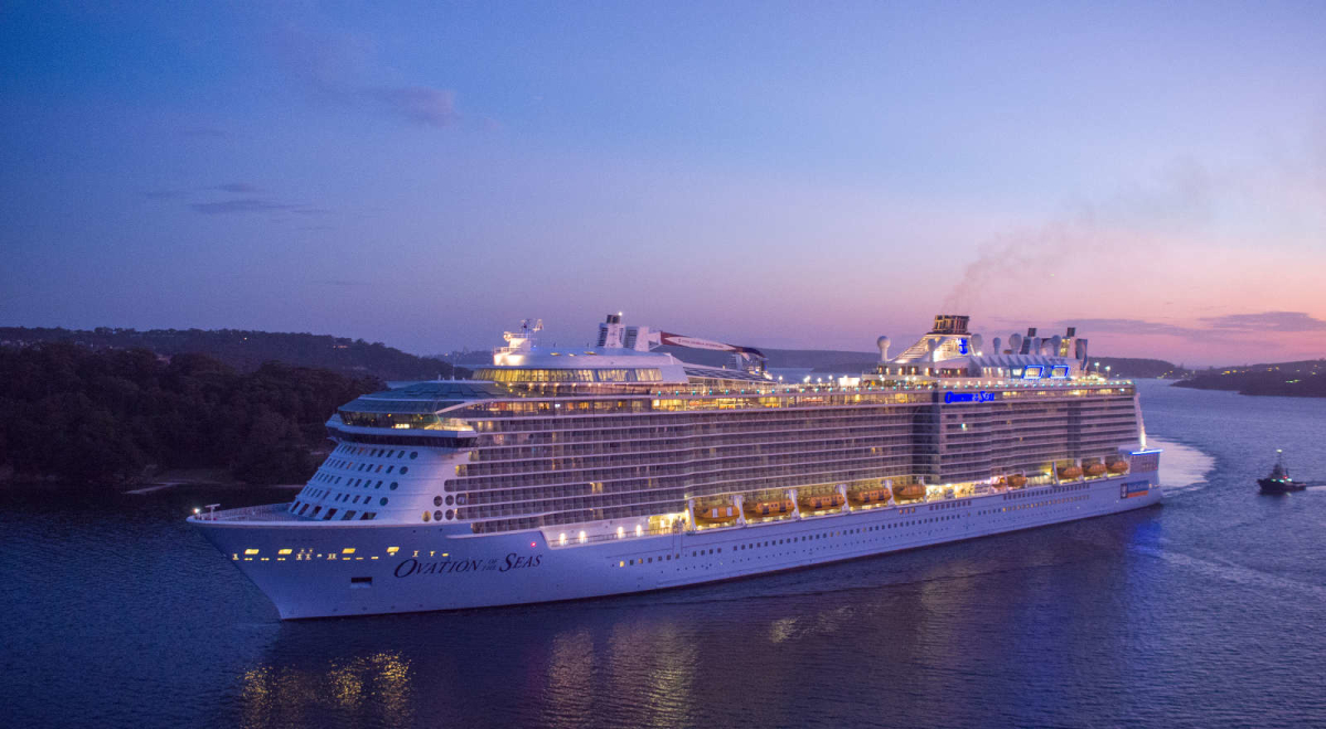 Large cruise ship lit up on the water during sunset 