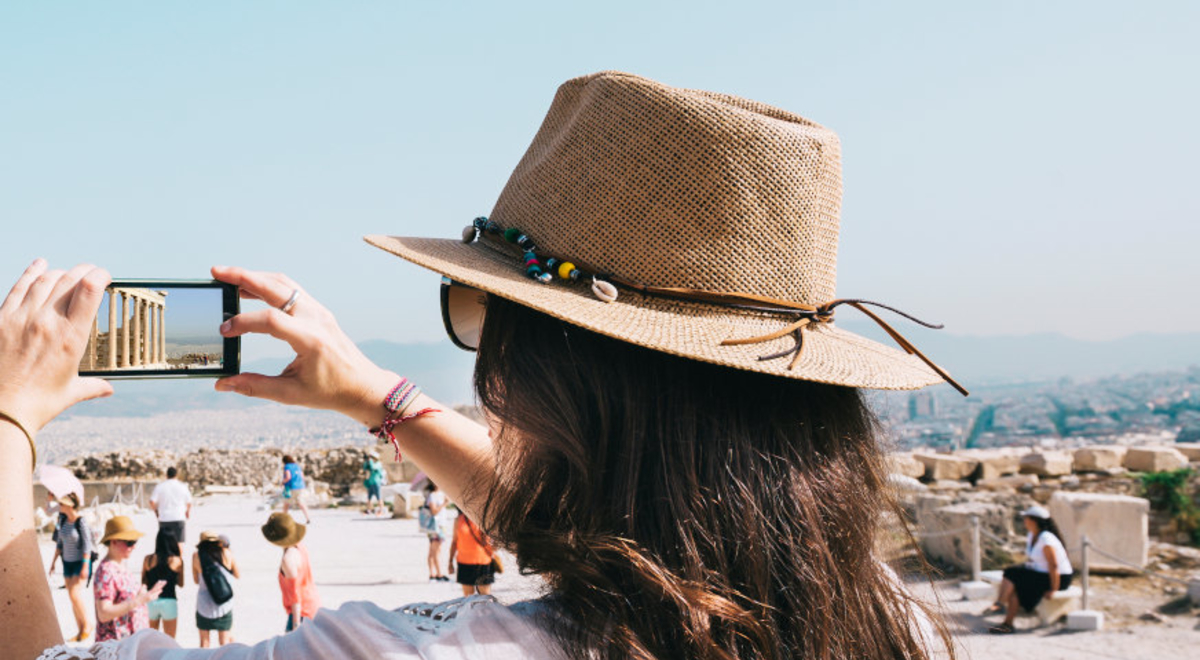 woman holding up a phone to take a photo of a structure in Athens