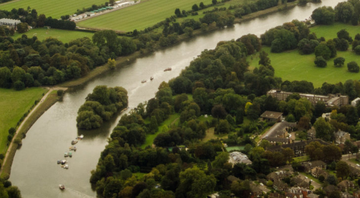 Settlement by a river surrounded by acres of green land and trees