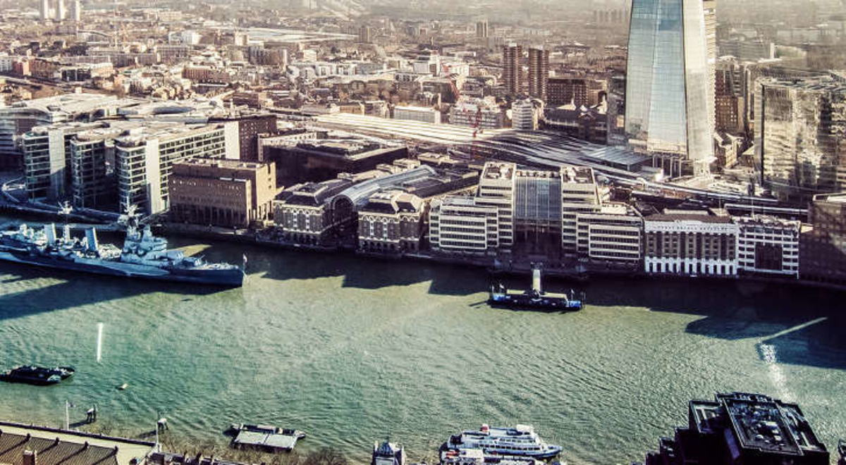 City buildings near the lake with a ship crossing and boats parking on the side