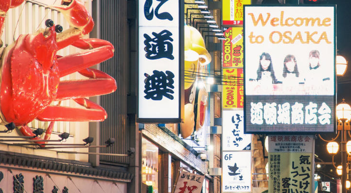 view of street in Osaka Japan with a welcome to Osaka illuminated lightbox signage
