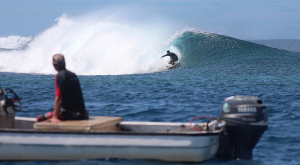 A surfer riding a wave in Samoa