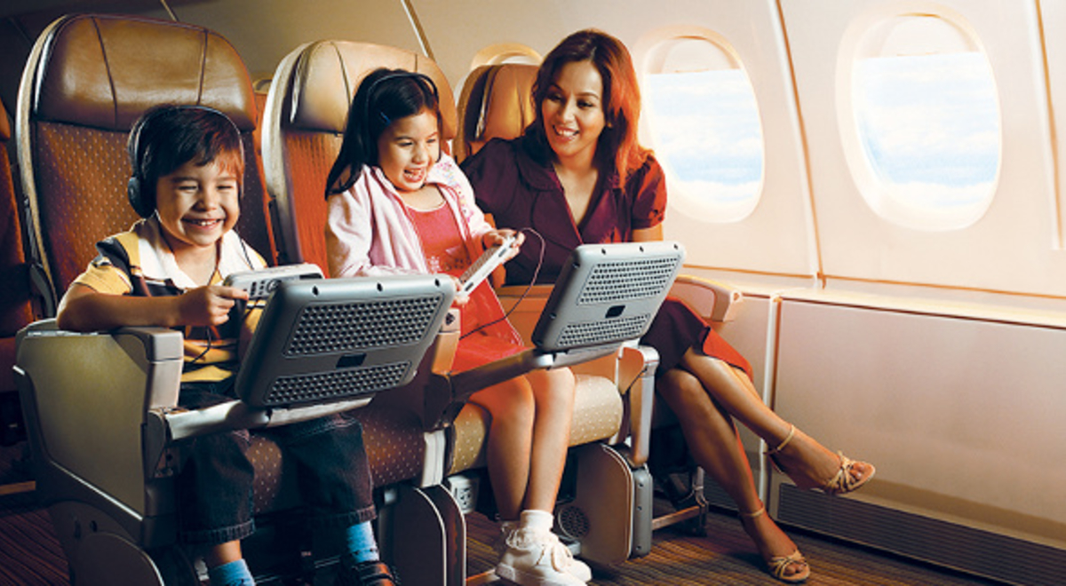 Mother and her two children playing video games in economy class