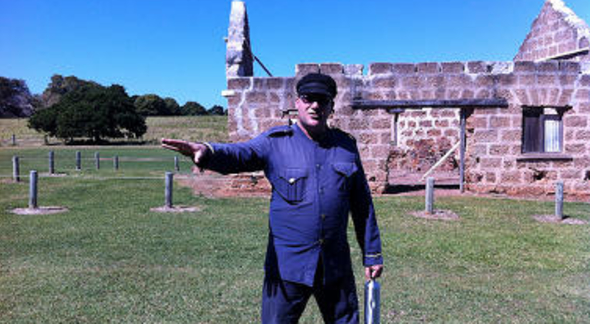 Warden explaining the story of a historical structure behind him