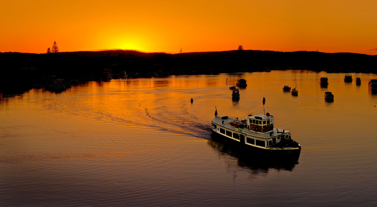 Boats at Port Stephens against an orange sky.