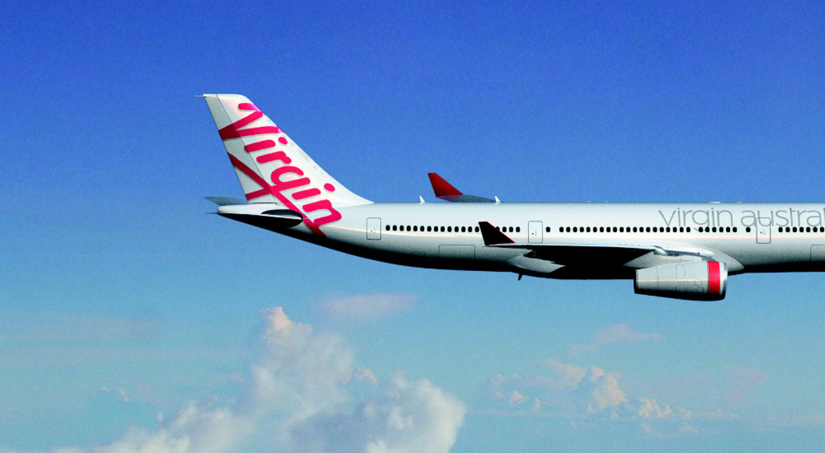 Virgin Australia airplane flying through blue skies with fluffy clouds in the background