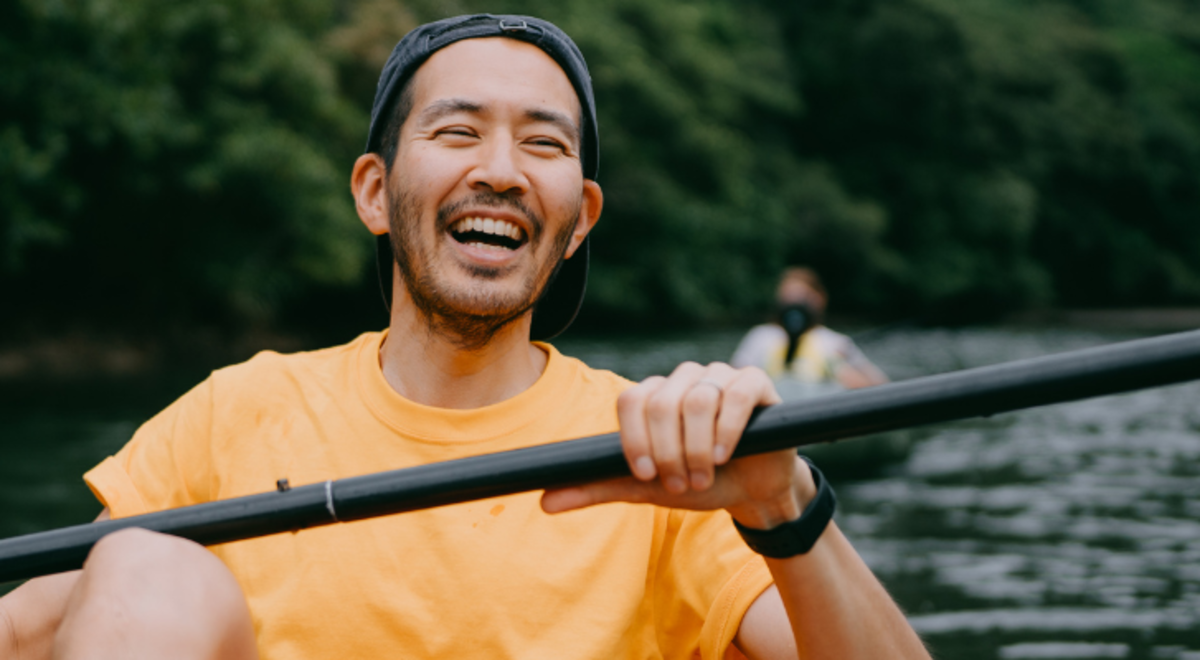 A guy smiling while canoeing in the river