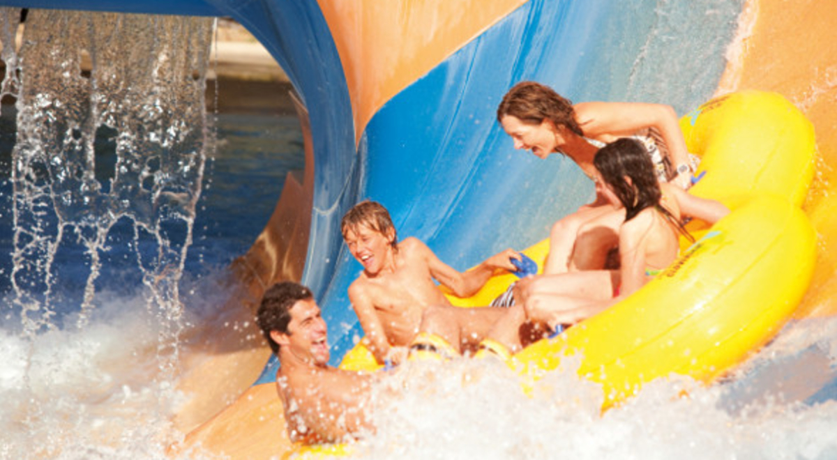 Family of four riding an inflatable in a waterpark slide