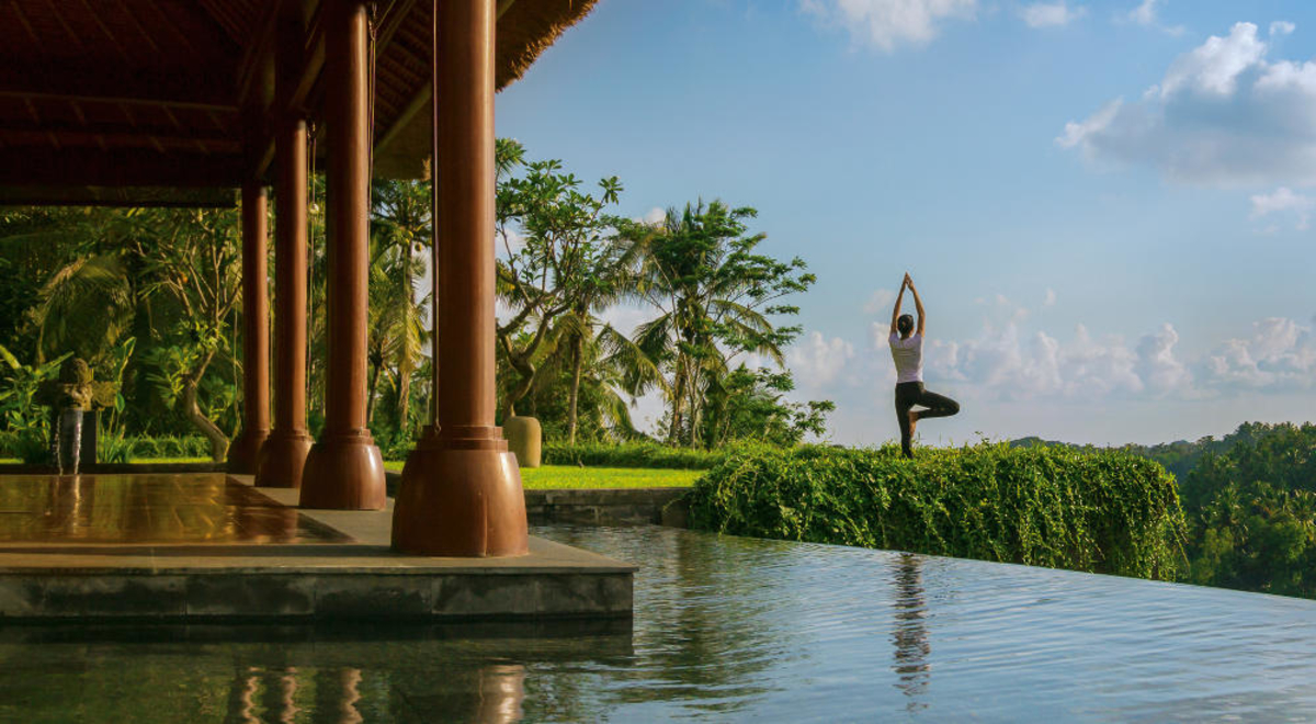 A woman performs yoga by a pool at Mandapa Ritz Carlton Ubud in Bali.