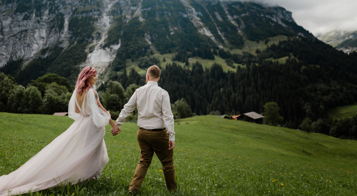 Bride and groom walking in a green alpine meadow