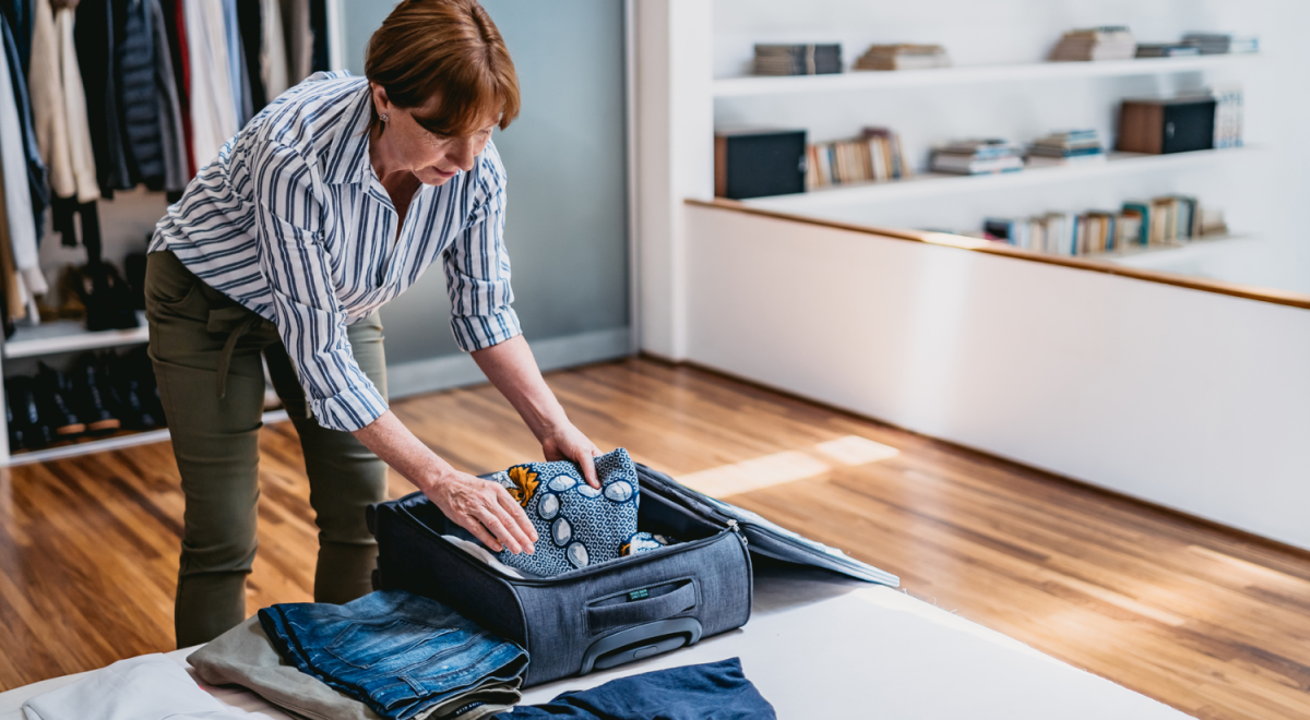 A senior woman packing a suitcase for a cruise vacation