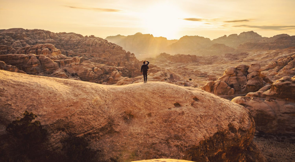 Person looking out as the sun sets over a rocky range