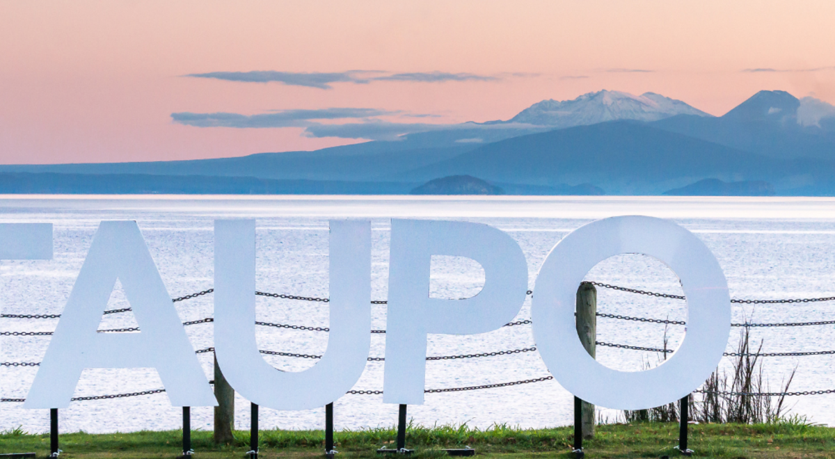 Taupo sign infront of Lake Taupo at sunset