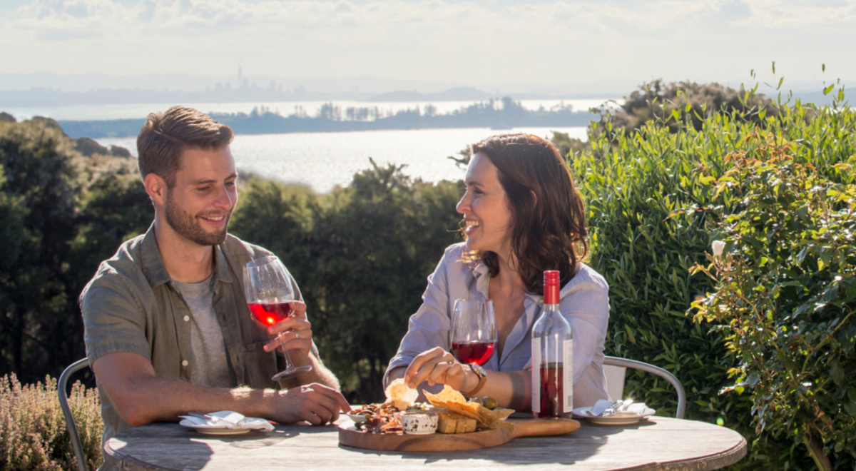 Couple drinking wine eating cheese platter with beautiful view in background