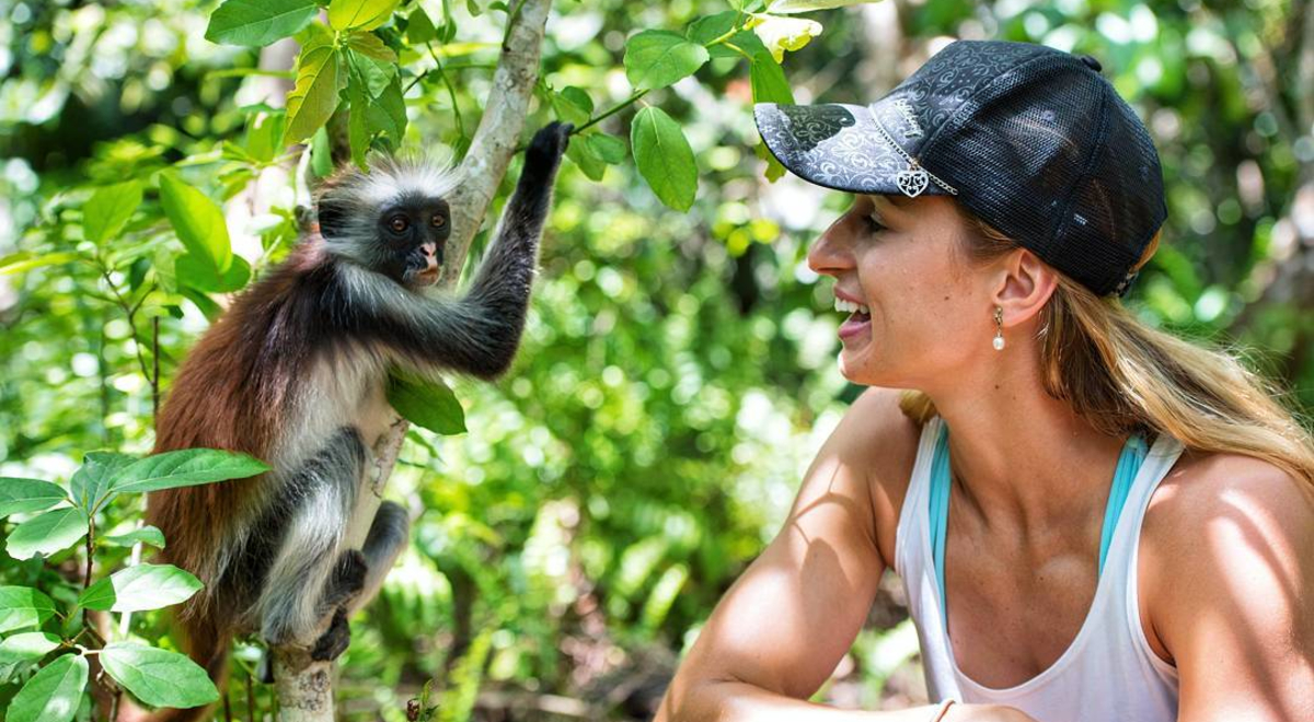 Woman wearing white shirt and black hat interacting with animal