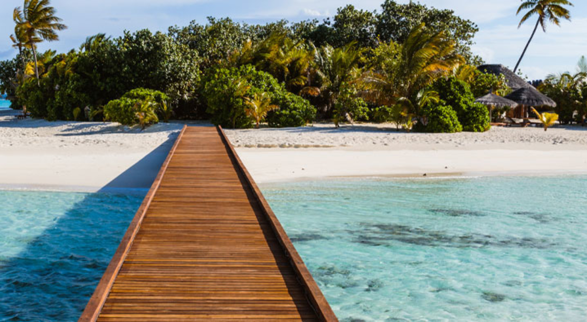 Bridge leading to white sand island surrounded by clear blue water 