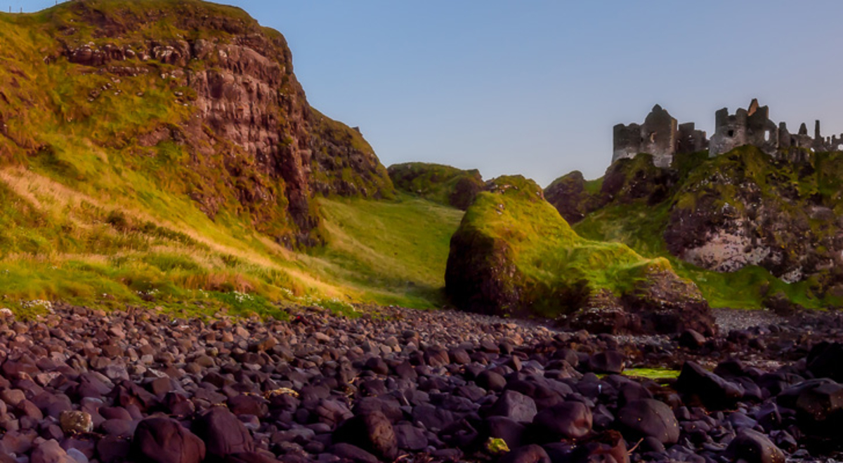 Sunset over the beach next to rocks and greenery