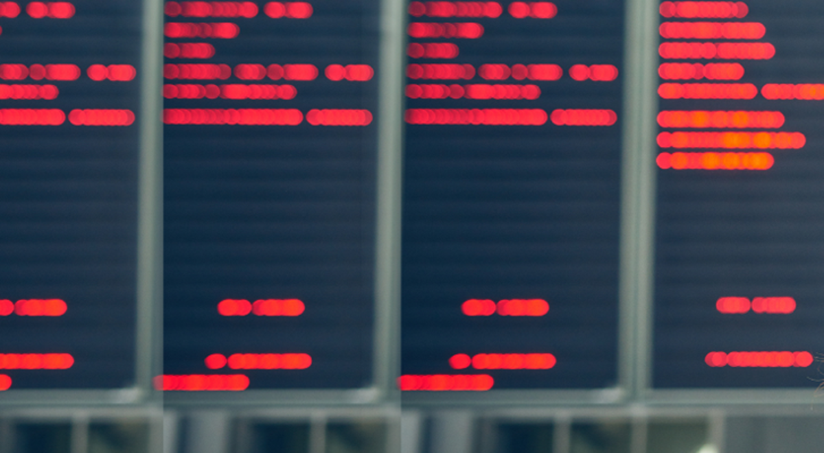 A woman traveller looks up at a digital departure board in an airport