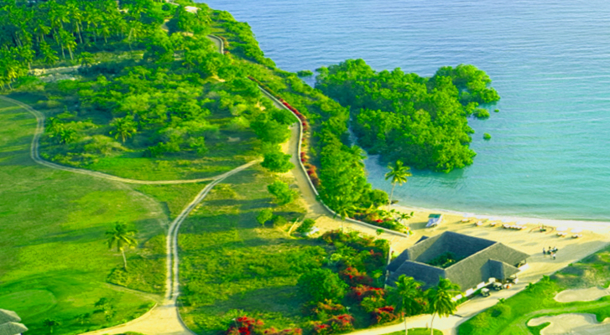 A drone's view of a beach-side golf course and boats moored near the shore