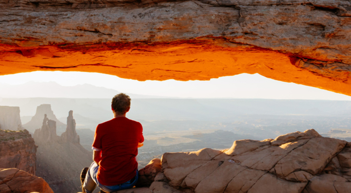 Man sitting on a rock admiring the skyline and view of red rocks
