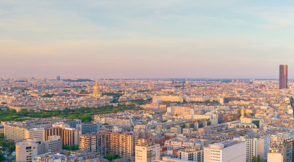 A panoramic aerial view of Paris at sunset with the Eiffel Tower in the center