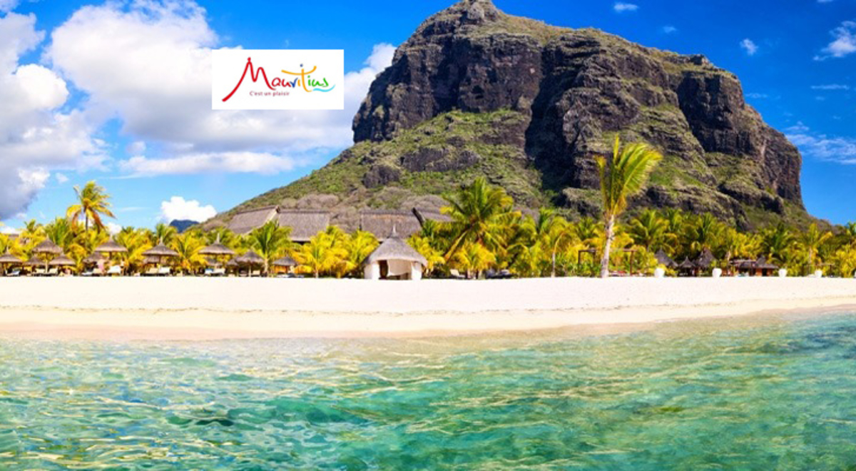 A view from a lagoon in Mauritius of the beach, palms and a mount of tall bluffs