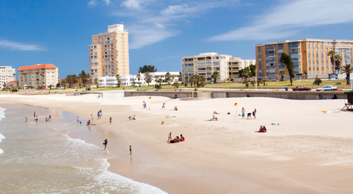 Waves breaking on a beautiful beach with a city in the background