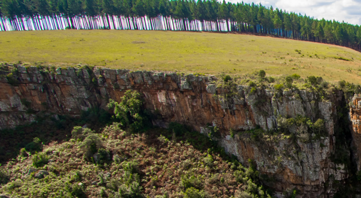 A panoramic view of a long cliff face with a waterfall cascading down the middle.