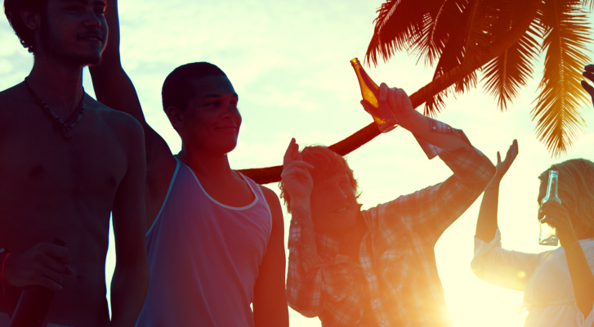 Group of 8 people dancing as the sunsets behind the palm tree in the distance