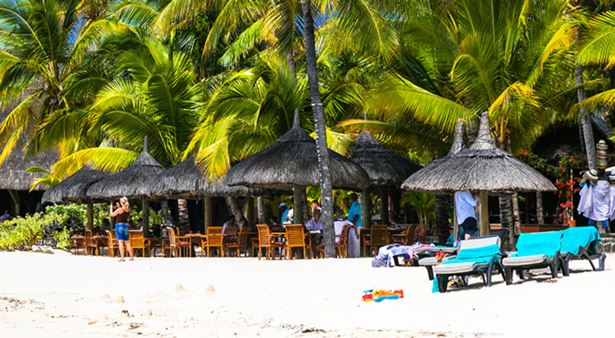 A beach in Mauritius with a villa and a palm tree