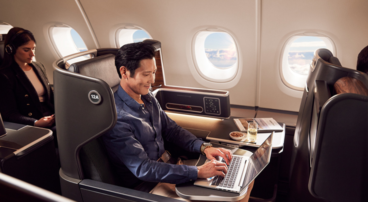 man sitting in business class on plane on his laptop