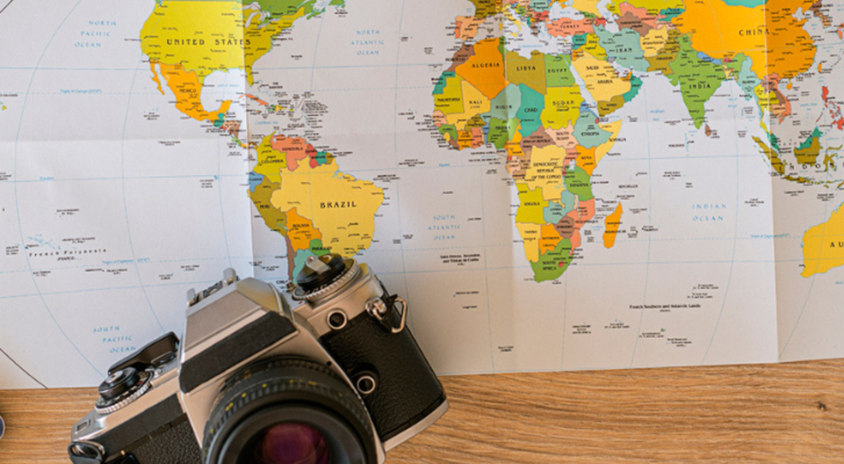 A map, camera, plane tickets and passport on a table