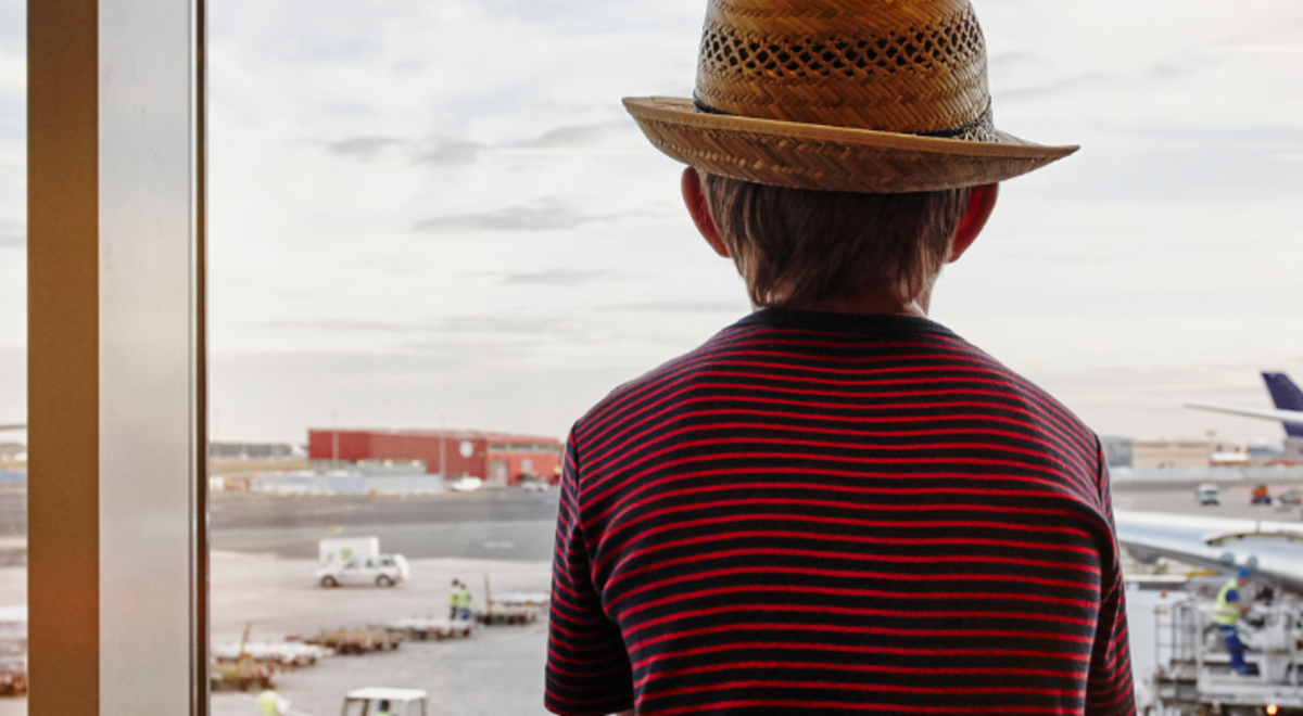 Young boy sitting in the airport looking out to the landed planes 