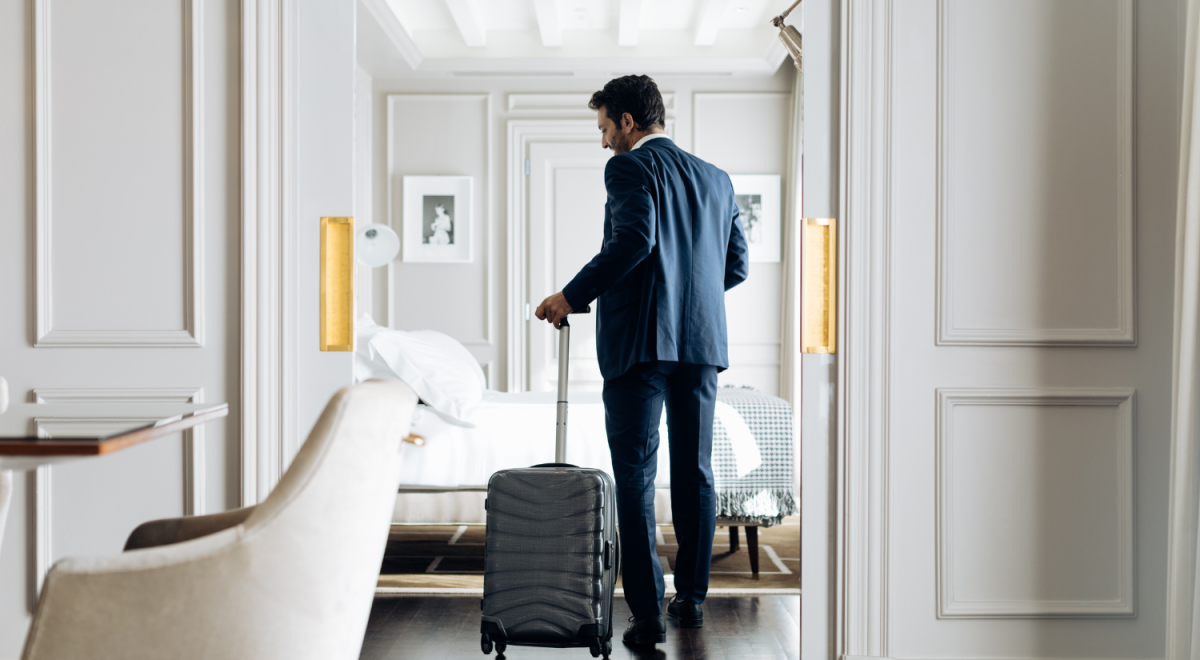 Man in a suit leaving the hotel room with his silver luggage