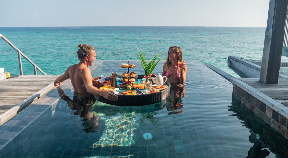 Couple eating breakfast at overwater bungalow