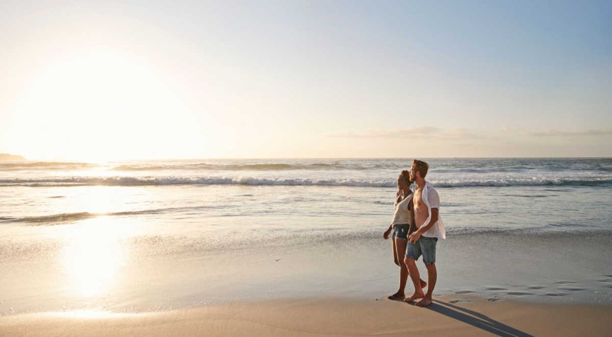 A loving couple walking on the beach as the sun rises