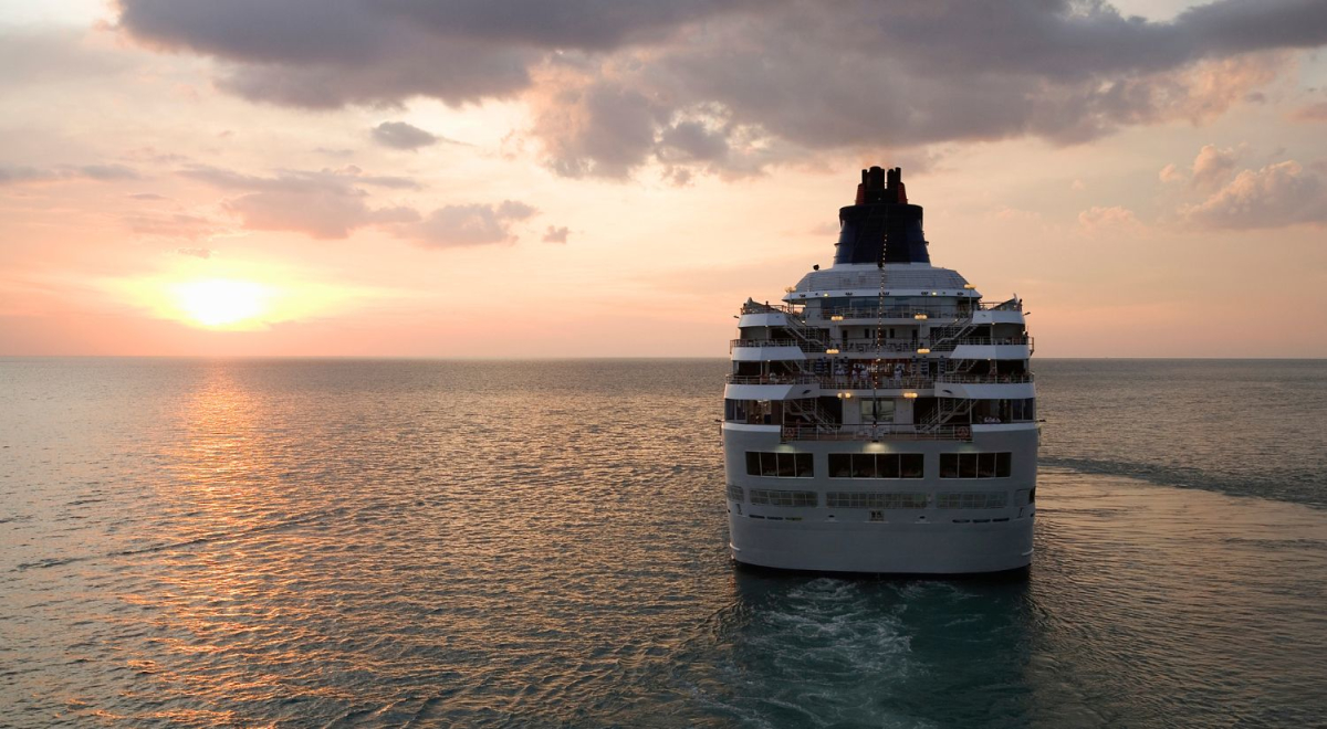 The view of a cruise ship from behind as it sails into the sunset