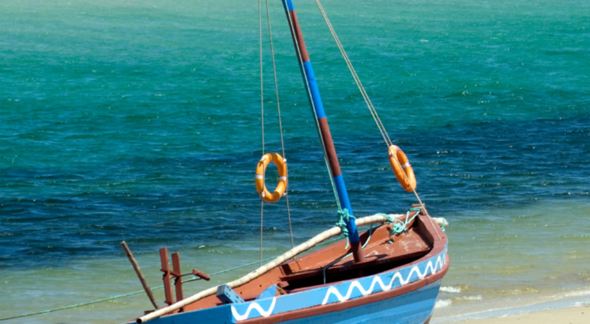 A small sail boat sitting on a beach