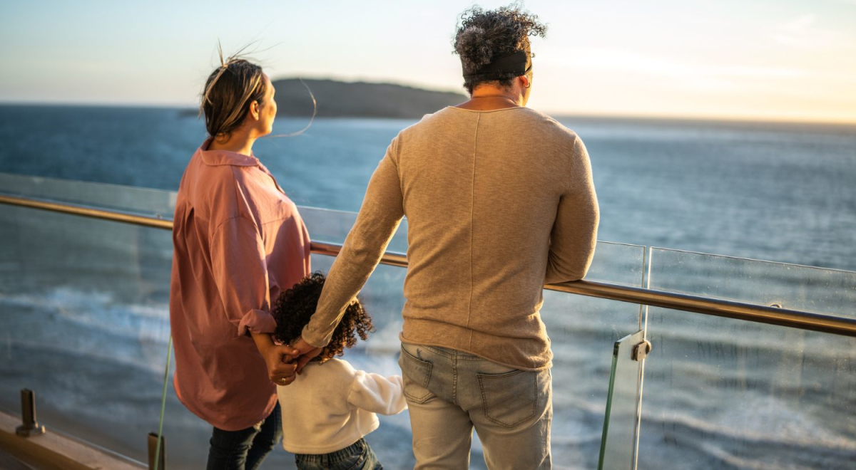 parents and child holding hands while child stands between them of deck of cruise ship 