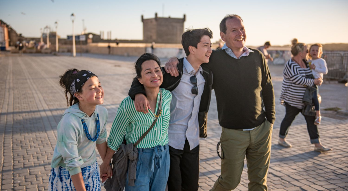 Family walking along beach with arms linked around each other