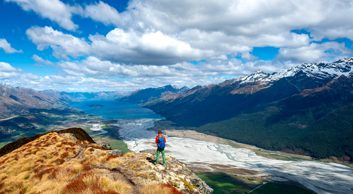 A person standing at the peak of a hiking trail near Queenstown, New Zealand