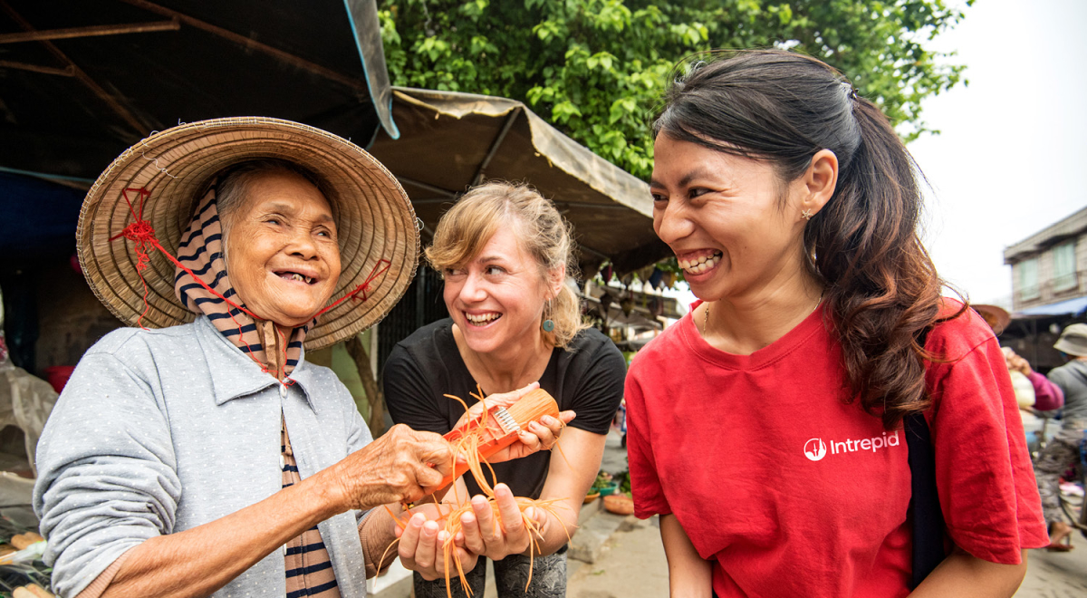 An Intrepid tour guide with a traveller and a food market vendor in Vietnam