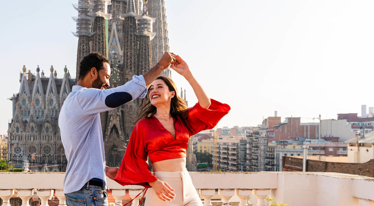 A couple dancing on a balcony that overlooks the Sagrada Familia in Barcelona