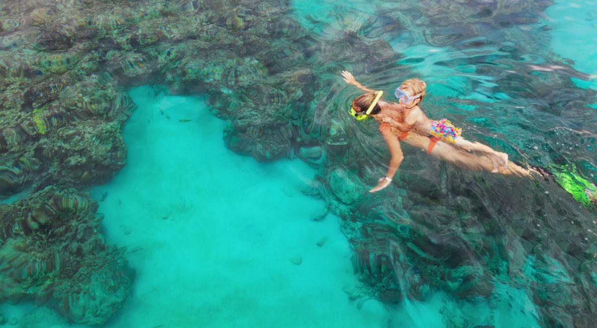 Mother, kid in snorkeling mask dive underwater with tropical fishes